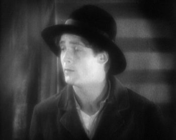 Movie still from “Street Angel” (1928), directed by Frank Borzage – A black and white photo of a man wearing a hat; Close Up shot, High angle