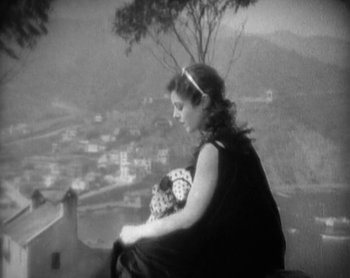Movie still from “Street Angel” (1928), directed by Frank Borzage – A woman sitting on top of a building near a tree; Medium shot, High angle