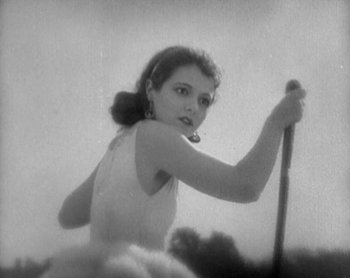 Movie still from “Street Angel” (1928), directed by Frank Borzage – A young woman holding a stick in a field; Close Up shot, Low angle