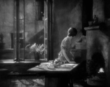 Movie still from “Street Angel” (1928), directed by Frank Borzage – An old photo of a woman sitting at a table in front of an open window; Wide shot, High angle