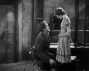 Movie still from “Street Angel” (1928), directed by Frank Borzage – A man kneeling down next to a woman in front of a fountain; Wide shot, High angle