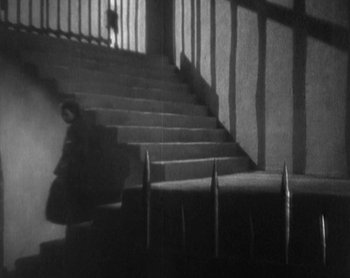 Movie still from “Street Angel” (1928), directed by Frank Borzage – A black and white photo of a person walking down a staircase; Extreme Wide shot, High angle