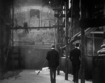 Movie still from “Street Angel” (1928), directed by Frank Borzage – Two men are walking in a building with scaffolding; Wide shot, High angle