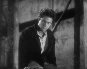 Movie still from “Street Angel” (1928), directed by Frank Borzage – A black and white photo of a man sitting in a chair; Medium shot, Low angle