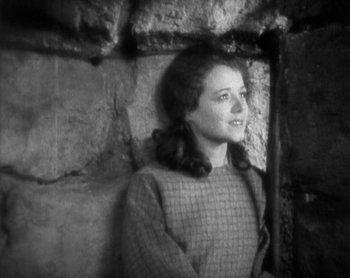 Movie still from “Street Angel” (1928), directed by Frank Borzage – A woman standing in front of a brick wall; Close Up shot, High angle