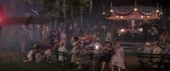Movie still from “Summer and Smoke” (1961), directed by Peter Glenville – A group of people sitting on lawn chairs in front of a building; Wide shot, High angle