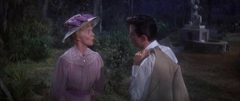 Movie still from “Summer and Smoke” (1961), directed by Peter Glenville – A man and a woman standing next to each other in front of trees; Medium shot, Over the shoulder angle