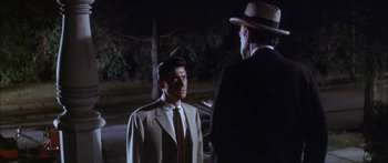 Movie still from “Summer and Smoke” (1961), directed by Peter Glenville – A man wearing a suit and tie talking to another man wearing a hat; Medium shot, Over the shoulder angle