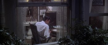 Movie still from “Summer and Smoke” (1961), directed by Peter Glenville – A man sitting at a desk in front of an open window; Wide shot, High angle