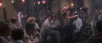 Movie still from “Summer and Smoke” (1961), directed by Peter Glenville – A group of men and women sitting around a table; Wide shot, Over the shoulder angle
