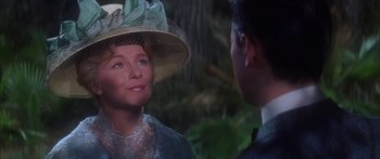 Movie still from “Summer and Smoke” (1961), directed by Peter Glenville – A woman wearing a hat talking to a man in a suit; Close Up shot, Over the shoulder angle