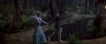 Movie still from “Summer and Smoke” (1961), directed by Peter Glenville – A man and a woman holding hands while walking through the woods; Wide shot, High angle
