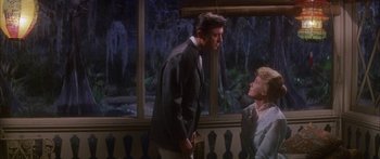 Movie still from “Summer and Smoke” (1961), directed by Peter Glenville – A man and a woman standing next to each other in front of a window; Medium shot, Over the shoulder angle