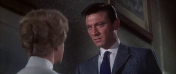 Movie still from “Summer and Smoke” (1961), directed by Peter Glenville – A man wearing a suit and tie talking to a woman; Close Up shot, Over the shoulder angle
