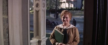 Movie still from “Summer and Smoke” (1961), directed by Peter Glenville – A woman holding a book in front of a building; Medium shot, High angle