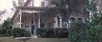 Movie still from “Summer and Smoke” (1961), directed by Peter Glenville – A man standing on a porch of an old house; Wide shot, Low angle