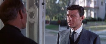 Movie still from “Summer and Smoke” (1961), directed by Peter Glenville – A man in a suit and tie standing in front of a door; Close Up shot, Over the shoulder angle