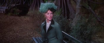 Movie still from “Summer and Smoke” (1961), directed by Peter Glenville – A woman sitting on top of a bench wearing a hat; Medium shot, Over the shoulder angle