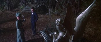 Movie still from “Summer and Smoke” (1961), directed by Peter Glenville – A man standing in front of a bench in the woods; Wide shot, High angle