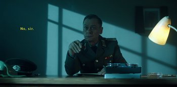 Movie still from “Fargo” (2014), created by Noah Hawley – A man sitting at a table in front of a window; Medium shot, Low angle