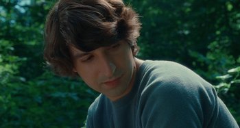 Movie still from “Taking Woodstock” (2009), directed by Ang Lee – A young man with long brown hair looking down at his face; Close Up shot, Over the shoulder angle