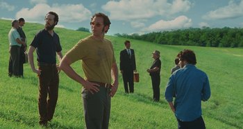 Movie still from “Taking Woodstock” (2009), directed by Ang Lee – A group of people standing in a grassy field; Medium shot, Low angle