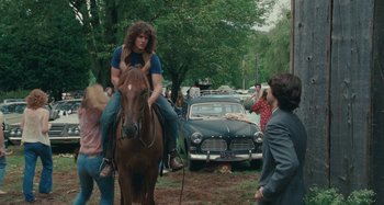 Movie still from “Taking Woodstock” (2009), directed by Ang Lee – A man riding a horse in a park with a crowd of onlookers; Wide shot, Over the shoulder angle