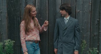Movie still from “Taking Woodstock” (2009), directed by Ang Lee – A man and a woman standing next to each other in front of a wooden wall; Medium shot, Over the shoulder angle