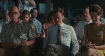 Movie still from “Taking Woodstock” (2009), directed by Ang Lee – A group of people sitting in front of a man; Medium shot, Over the shoulder angle