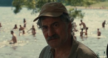 Movie still from “Taking Woodstock” (2009), directed by Ang Lee – An older man wearing a hat in front of a body of water; Close Up shot, Over the shoulder angle