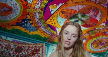 Movie still from “Taking Woodstock” (2009), directed by Ang Lee – A woman standing in front of a colorful mural; Medium shot, Overhead angle