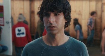 Movie still from “Taking Woodstock” (2009), directed by Ang Lee – A young man with long black hair is looking at the camera; Close Up shot, Over the shoulder angle