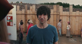 Movie still from “Taking Woodstock” (2009), directed by Ang Lee – A young man standing in front of a wooden fence; Medium shot, Over the shoulder angle