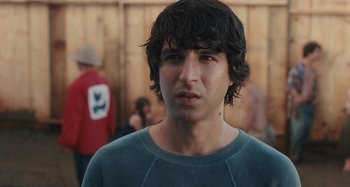 Movie still from “Taking Woodstock” (2009), directed by Ang Lee – A man with long black hair is looking at the camera; Close Up shot, Over the shoulder angle