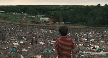 Movie still from “Taking Woodstock” (2009), directed by Ang Lee – A man standing in the middle of a muddy field; Extreme Wide shot, High angle