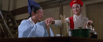 Two people sitting at a table with chopsticks in their hands