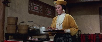 A woman holding a tray in front of a tea pot