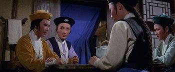 A woman sitting in front of another woman in front of a blue curtain