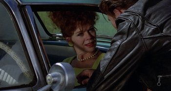 Movie still from “The Loveless” (1981), directed by Kathryn Bigelow – A woman sitting in the back of a car next to a man in a leather jacket; Close Up shot, Over the shoulder angle