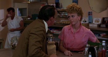 Movie still from “The Loveless” (1981), directed by Kathryn Bigelow – An older man and woman sitting at a table talking to each other; Medium shot, Over the shoulder angle