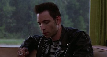 Movie still from “The Loveless” (1981), directed by Kathryn Bigelow – A man in a leather jacket looking at his watch; Close Up shot, Low angle