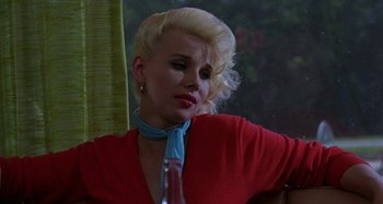 Movie still from “The Loveless” (1981), directed by Kathryn Bigelow – A woman with blonde hair wearing a red shirt and a blue neck tie; Close Up shot, Low angle