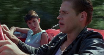 Movie still from “The Loveless” (1981), directed by Kathryn Bigelow – A man and a woman sitting in a red car; Close Up shot, Over the shoulder angle