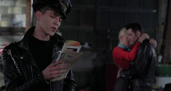 Movie still from “The Loveless” (1981), directed by Kathryn Bigelow – A man in a leather jacket reading a newspaper; Medium shot, Over the shoulder angle