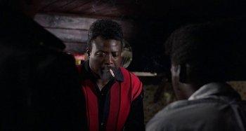 Movie still from “The Loveless” (1981), directed by Kathryn Bigelow – A man smoking a cigarette while standing next to another man; Medium shot, Over the shoulder angle