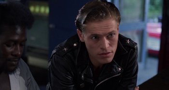 Movie still from “The Loveless” (1981), directed by Kathryn Bigelow – A person wearing a leather jacket; Close Up shot, Over the shoulder angle