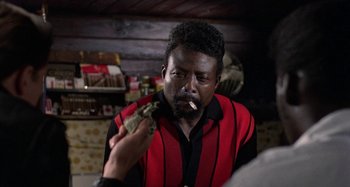 Movie still from “The Loveless” (1981), directed by Kathryn Bigelow – A man in a red and black striped shirt is smoking a cigarette; Close Up shot, Over the shoulder angle