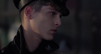 Movie still from “The Loveless” (1981), directed by Kathryn Bigelow – A young man wearing a leather cap and jacket; Close Up shot, Over the shoulder angle