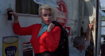 Movie still from “The Loveless” (1981), directed by Kathryn Bigelow – A woman in a red shirt and a blue neck scarf holding an umbrella over her shoulder; Medium shot, Low angle