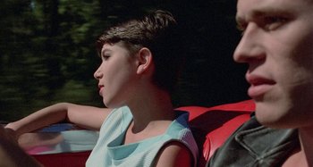 Movie still from “The Loveless” (1981), directed by Kathryn Bigelow – A woman sitting in the back of a red car; Close Up shot, Over the shoulder angle